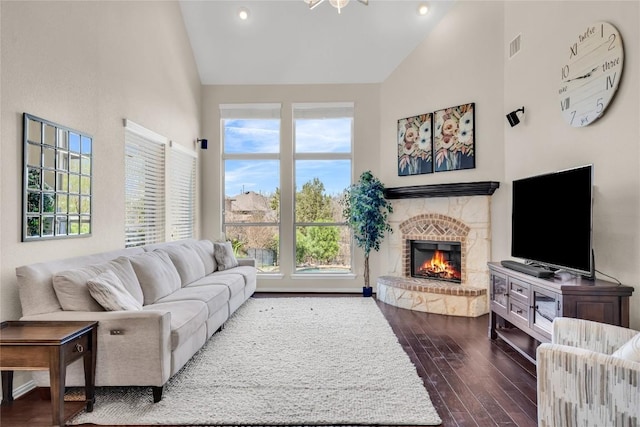 3925 Good Night Trl, Leander, TX 78641 - living area with high vaulted ceiling, a warm lit fireplace, dark wood-style floors, recessed lighting, and baseboards
