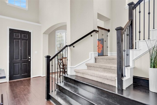 3925 Good Night Trl, Leander, TX 78641 - foyer entrance with a high ceiling, stairway, arched walkways, and dark wood finished floors