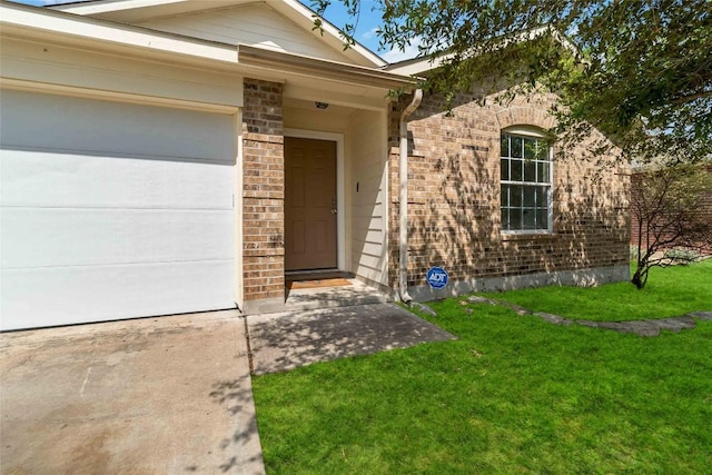 804 Lavaca Loop, Elgin, TX 78621 - view of exterior entry with brick siding, a yard, driveway, and an attached garage