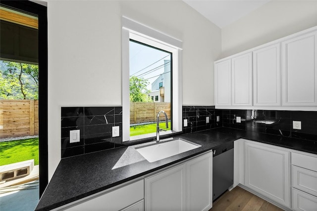 3306 Larry Ln Unit B, Austin, TX 78722 - kitchen with stainless steel dishwasher, dark countertops, white cabinets, and backsplash