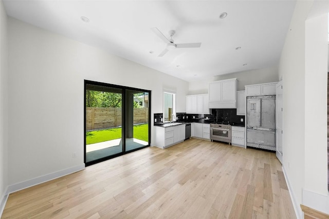 3306 Larry Ln Unit B, Austin, TX 78722 - kitchen featuring stainless steel appliances, backsplash, white cabinetry, light wood-type flooring, and dark countertops