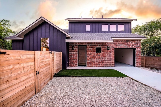 3306 Larry Ln Unit B, Austin, TX 78722 - back of house with driveway, board and batten siding, roof with shingles, an attached garage, and brick siding