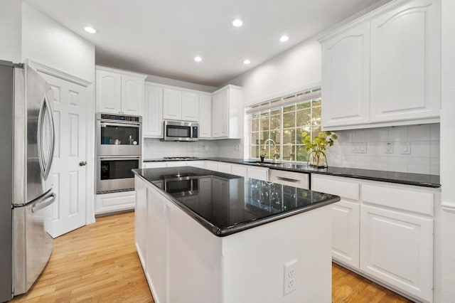 5204 Eagle Trace Trl, Austin, TX 78730 - kitchen featuring appliances with stainless steel finishes, white cabinetry, backsplash, light wood finished floors, and recessed lighting