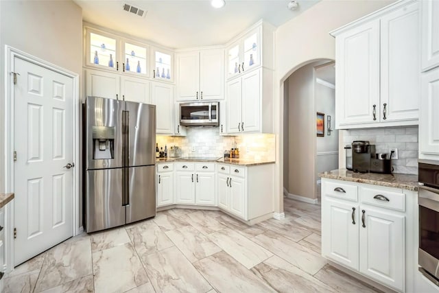 3028 Indigo Trl, Round Rock, TX 78665 - kitchen with appliances with stainless steel finishes, arched walkways, light stone countertops, white cabinets, and recessed lighting