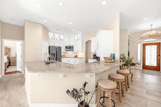 3028 Indigo Trl, Round Rock, TX 78665 - kitchen with appliances with stainless steel finishes, a peninsula, a sink, light stone countertops, and white cabinetry
