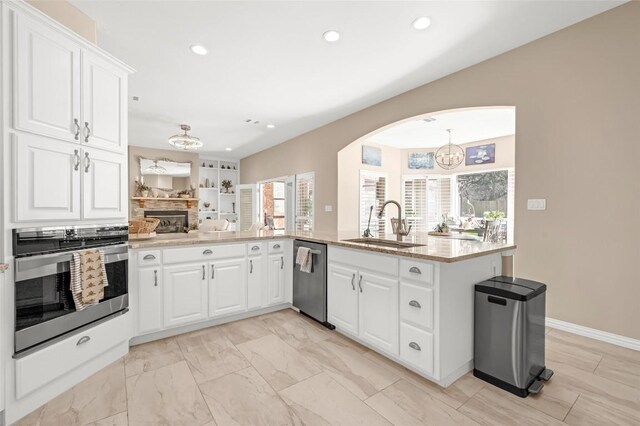 3028 Indigo Trl, Round Rock, TX 78665 - kitchen with stainless steel appliances, a sink, white cabinets, recessed lighting, and a fireplace
