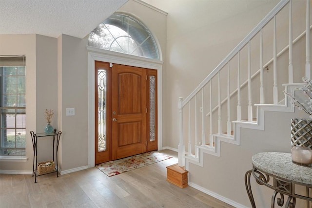 foyer featuring stairway, wood finished floors, and baseboards
