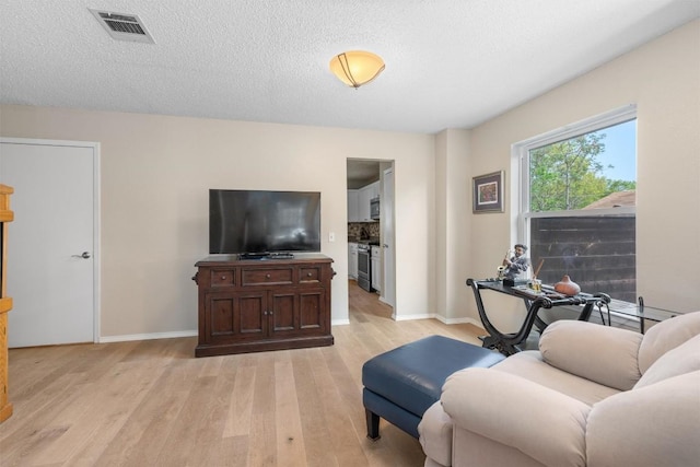 living room featuring baseboards, visible vents, and light wood-type flooring
