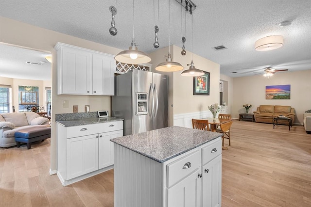 kitchen with stainless steel fridge, light wood-style floors, a kitchen island, visible vents, and open floor plan