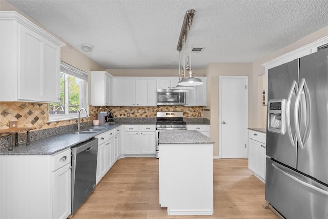 kitchen with a textured ceiling, a sink, stainless steel appliances, and light wood-style floors