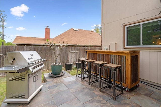 view of patio featuring fence, area for grilling, and outdoor dry bar