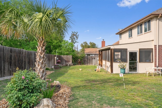 view of yard featuring a fenced backyard and a sunroom