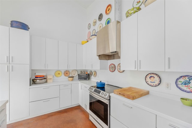 kitchen with a toaster, light countertops, wall chimney exhaust hood, white cabinetry, and range with electric cooktop