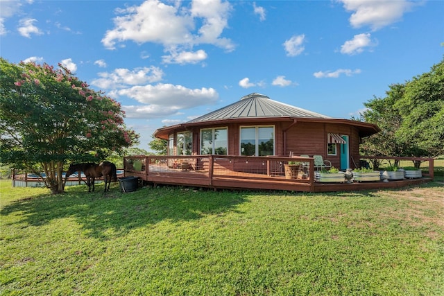 back of property featuring a lawn, a wooden deck, a standing seam roof, and metal roof