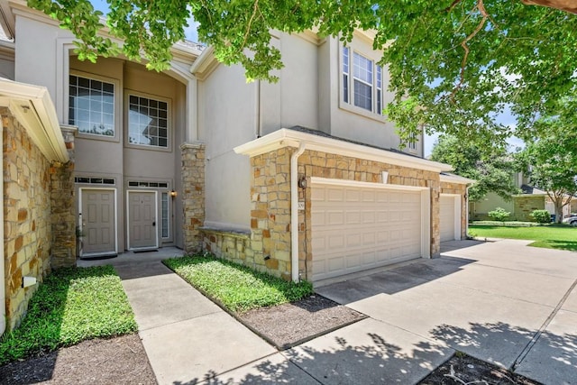 view of front of house with driveway, stucco siding, and stone siding