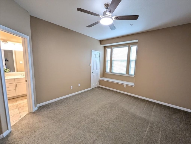 unfurnished bedroom with baseboards, a ceiling fan, connected bathroom, and carpet