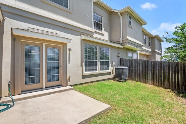 back of property with central AC, a lawn, fence, a patio, and stucco siding
