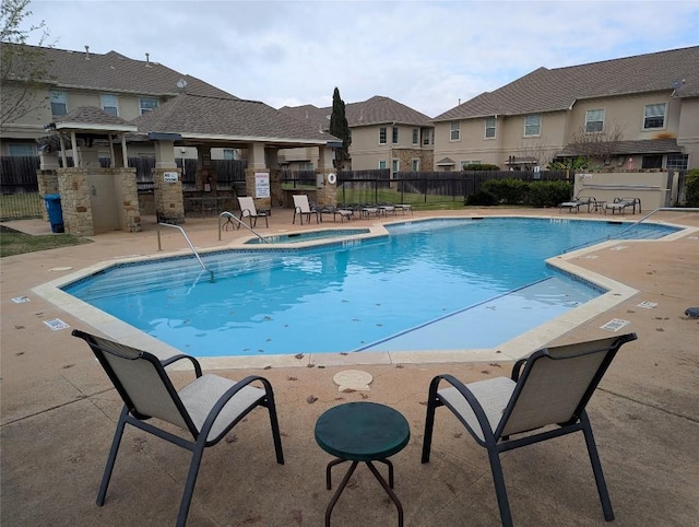 community pool with a patio area, fence, a residential view, and a wall unit AC