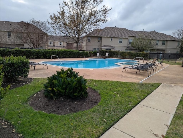 community pool with a patio area, fence, and a lawn