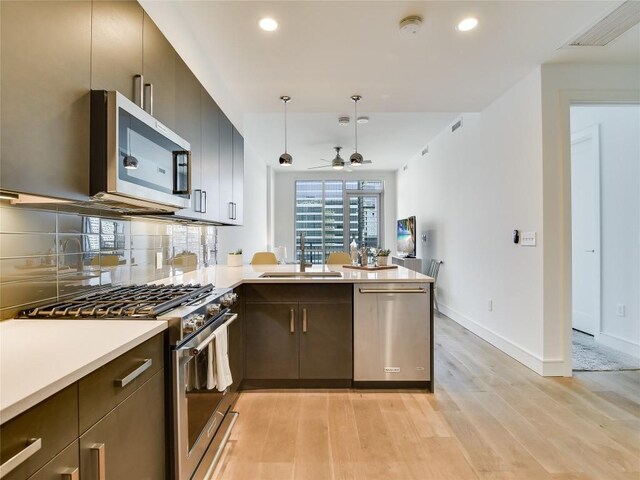 222 W Ave Unit 1907, Austin, TX 78701 - kitchen featuring appliances with stainless steel finishes, light wood-type flooring, a peninsula, light countertops, and a ceiling fan