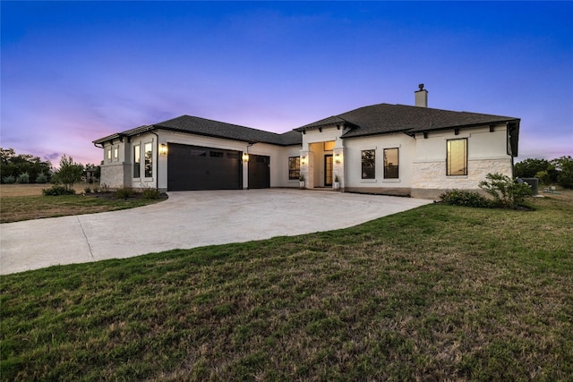 prairie-style house featuring concrete driveway, a chimney, stucco siding, a lawn, and a garage