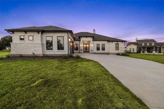 view of front of home with stucco siding, a chimney, curved driveway, and a front yard
