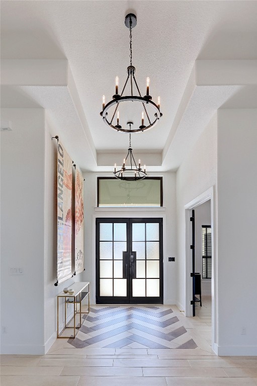 entrance foyer featuring baseboards, a notable chandelier, and a raised ceiling
