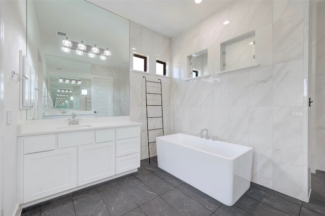 full bathroom featuring vanity, tile walls, a soaking tub, marble finish floor, and walk in shower