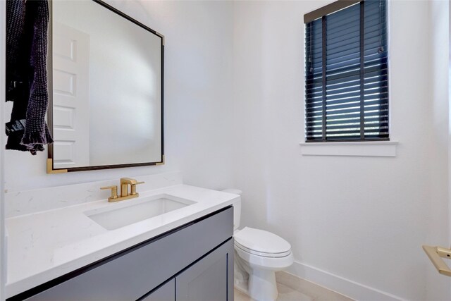 bathroom with baseboards, toilet, and vanity
