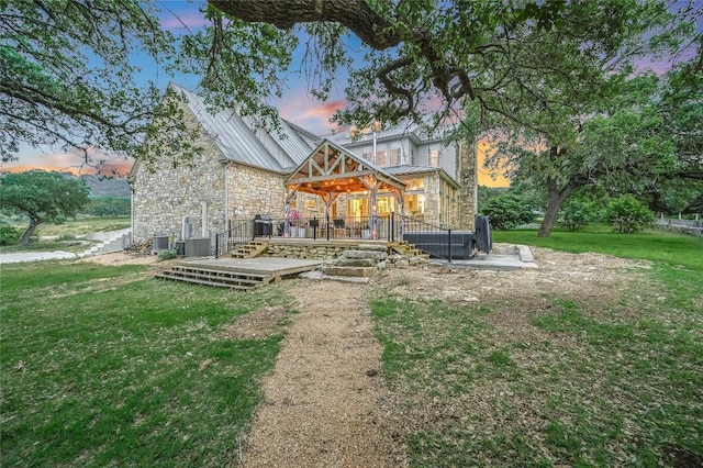 1174 Royal Eagle Dr, Fischer, TX 78623 - back of property with stone siding, a standing seam roof, a wooden deck, a yard, and metal roof
