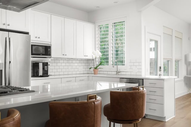 2517 Exposition Blvd, Austin, TX 78703 - kitchen featuring stainless steel appliances, a sink, tasteful backsplash, white cabinets, and a kitchen bar