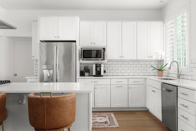 2517 Exposition Blvd, Austin, TX 78703 - kitchen featuring stainless steel appliances, a sink, wall chimney exhaust hood, backsplash, and white cabinetry