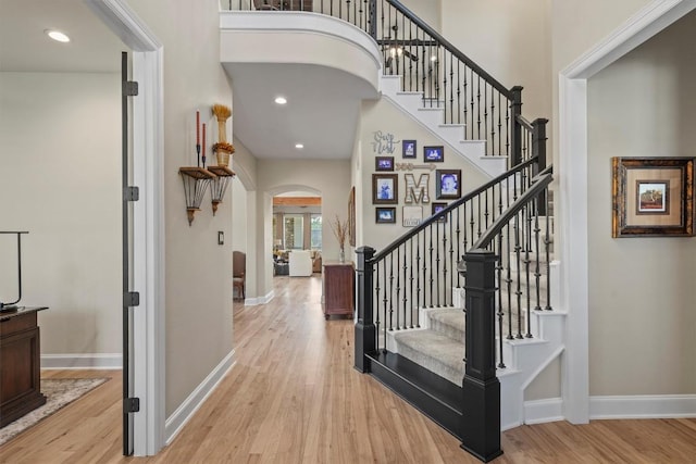 entrance foyer featuring light wood-style flooring, baseboards, and arched walkways