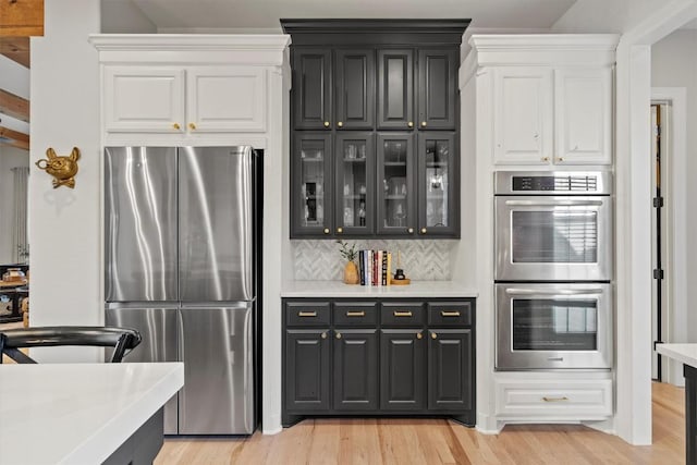 kitchen with white cabinetry, stainless steel appliances, light wood-style floors, and light countertops