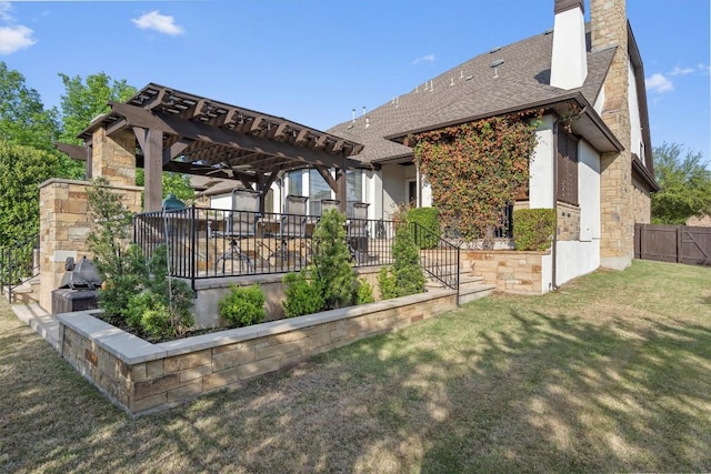 back of house featuring stone siding, a chimney, fence, a pergola, and a yard