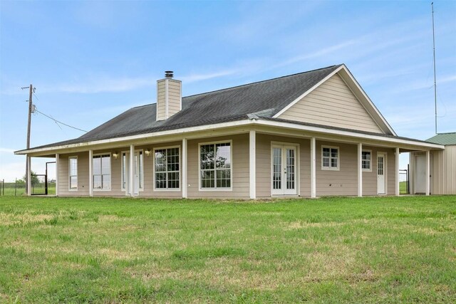 back of property with a lawn, a chimney, and roof with shingles