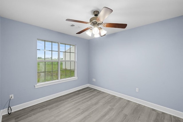 unfurnished room with baseboards, visible vents, wood finished floors, and ceiling fan