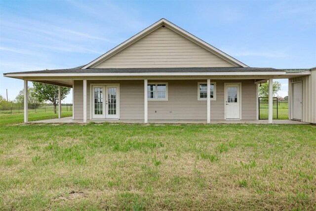 back of house featuring french doors, roof with shingles, and a lawn