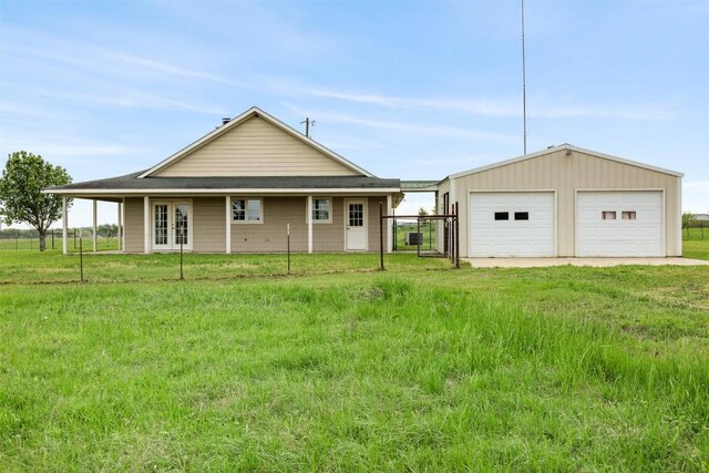exterior space with a front lawn, a detached garage, an outdoor structure, and french doors
