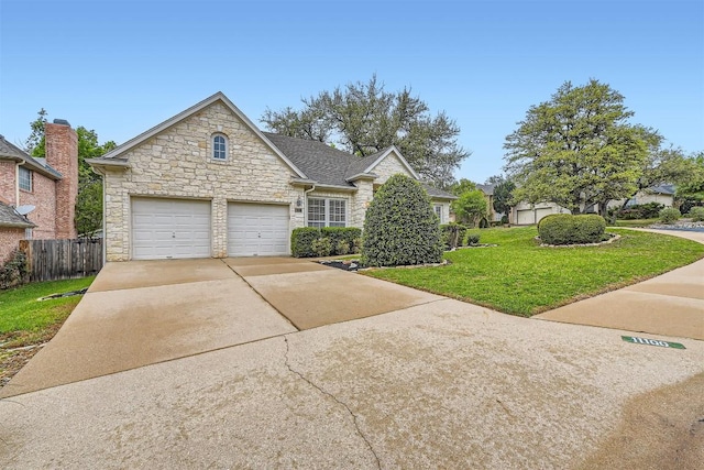 traditional home featuring stone siding, a front yard, concrete driveway, and fence