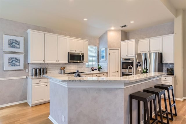 11100 Comiso Pala Path, Austin, TX 78726 - kitchen featuring appliances with stainless steel finishes, a center island with sink, light wood-type flooring, white cabinetry, and recessed lighting
