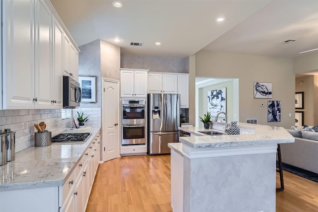 kitchen featuring a sink, light wood finished floors, appliances with stainless steel finishes, visible vents, and white cabinets