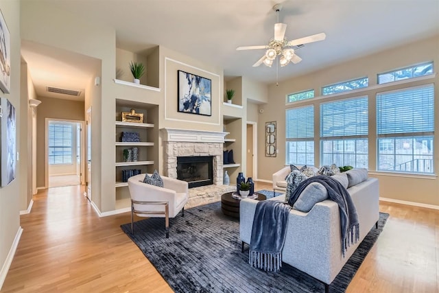 11100 Comiso Pala Path, Austin, TX 78726 - living area featuring light wood-style flooring, plenty of natural light, a stone fireplace, and a ceiling fan