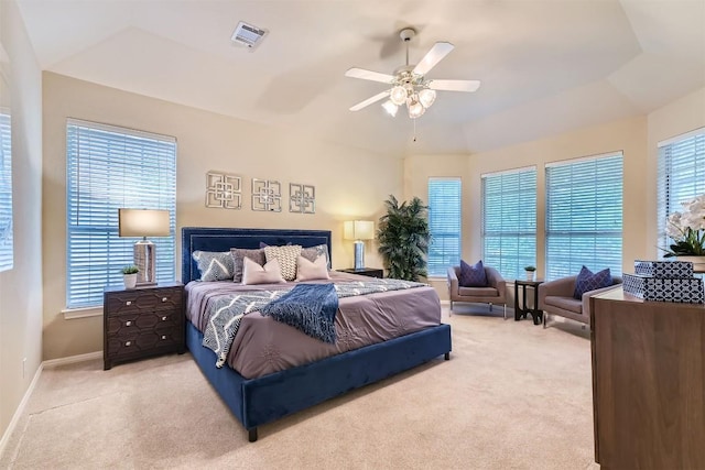 carpeted bedroom featuring a tray ceiling, baseboards, ceiling fan, and visible vents