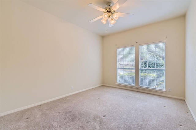 carpeted spare room with baseboards and a ceiling fan