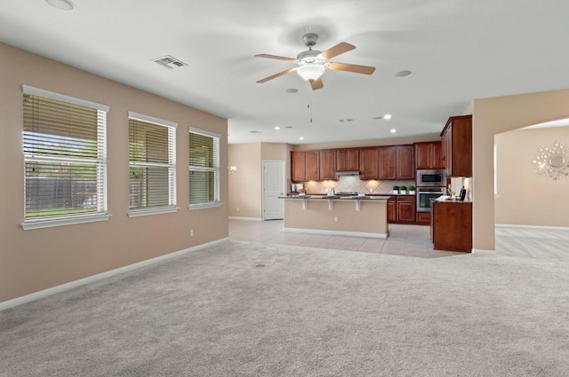 17920 Silent Harbor Loop, Pflugerville, TX 78660 - kitchen with appliances with stainless steel finishes, light colored carpet, ceiling fan, backsplash, and a center island with sink