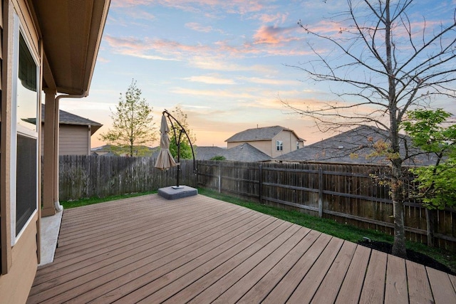 deck at dusk featuring a fenced backyard