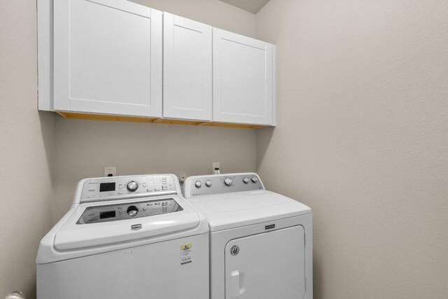 washroom with cabinet space and separate washer and dryer