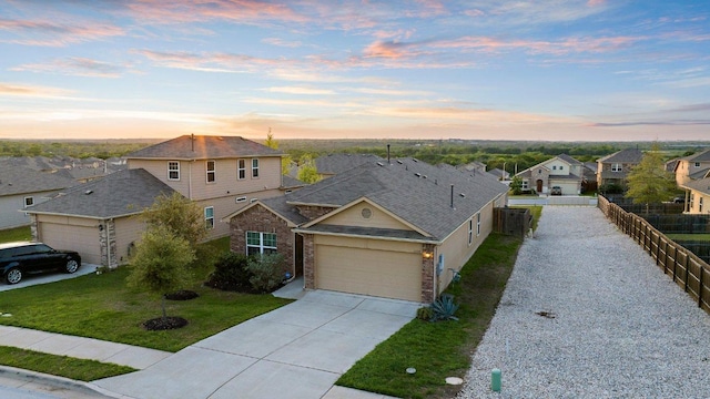 traditional-style house with driveway, fence, an attached garage, brick siding, and a lawn