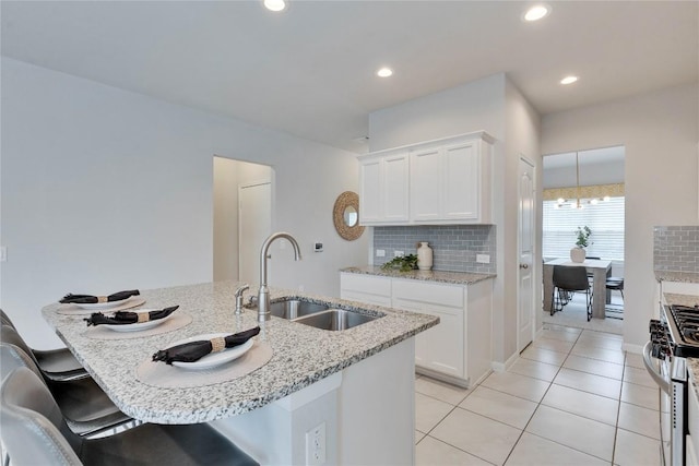 6608 May Shower Dr, Austin, TX 78744 - kitchen with a sink, stainless steel gas range, decorative backsplash, light tile patterned floors, and white cabinetry